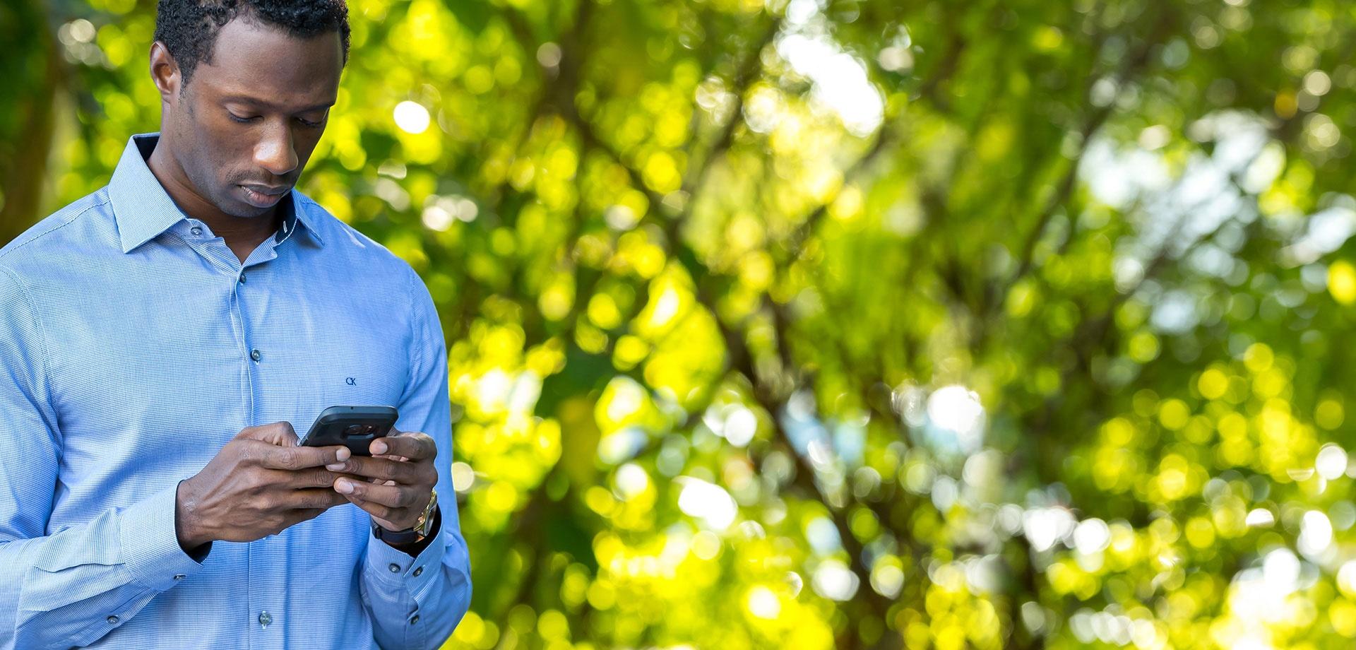 Man focussed on his smartphone wearing a light blue long sleeve shirt